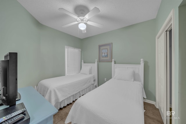 tiled bedroom with a textured ceiling and ceiling fan