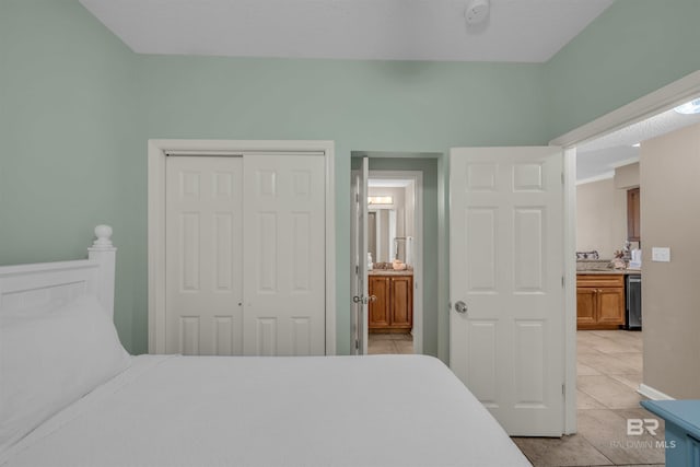 bedroom with light tile patterned floors, a closet, and ensuite bathroom