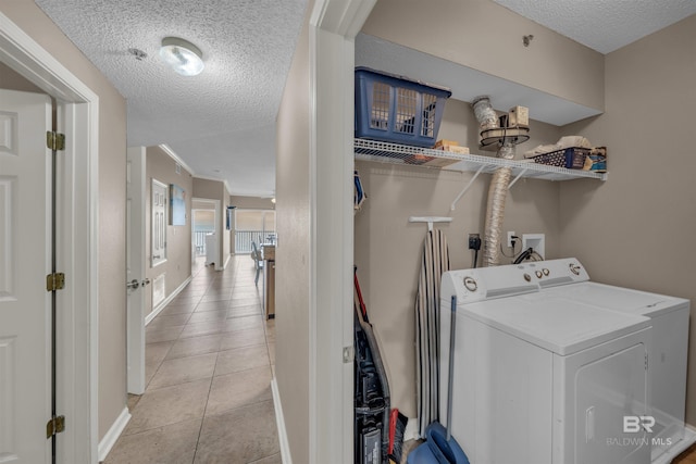 laundry room with light tile patterned floors, baseboards, washing machine and clothes dryer, laundry area, and a textured ceiling