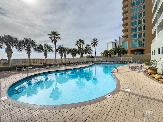 community pool with a patio area and fence