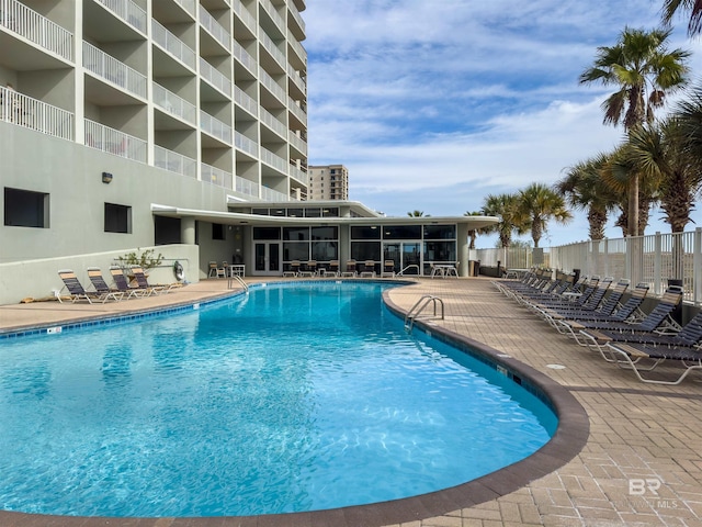 community pool with a patio area and fence