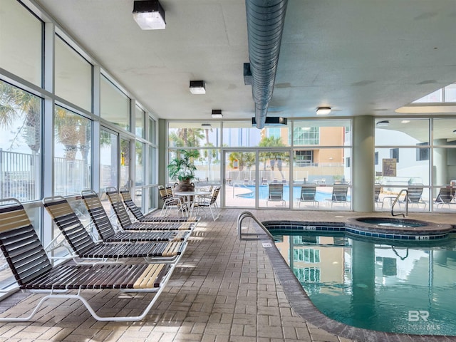 pool featuring a patio area, glass enclosure, and an indoor hot tub