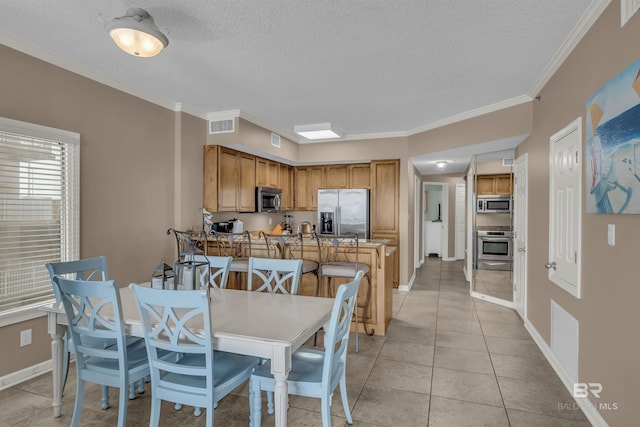 dining room featuring visible vents, baseboards, light tile patterned flooring, and ornamental molding