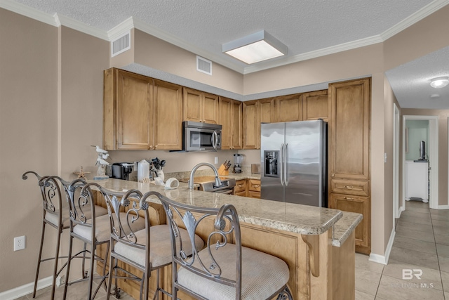 kitchen featuring stainless steel appliances, a kitchen bar, visible vents, and a peninsula