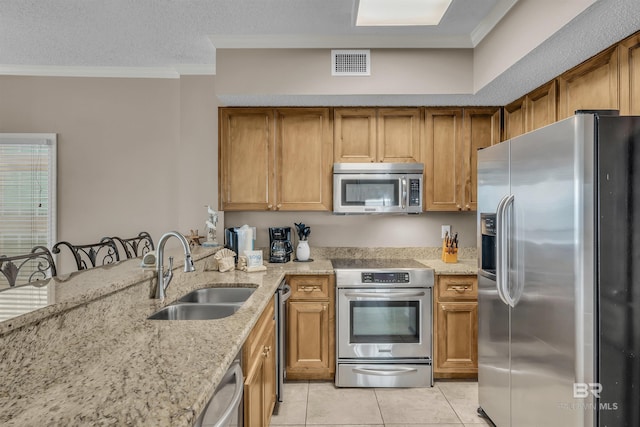 kitchen with light stone countertops, visible vents, a sink, appliances with stainless steel finishes, and crown molding