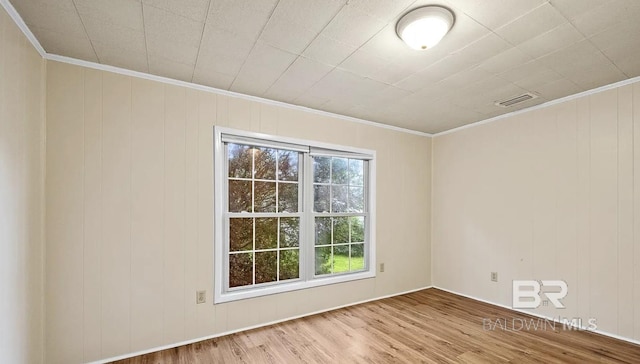 spare room with crown molding, hardwood / wood-style flooring, and wooden walls