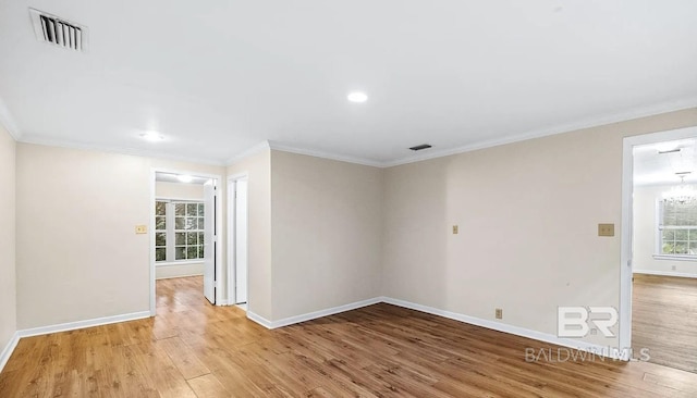 empty room with light hardwood / wood-style floors, crown molding, and a chandelier