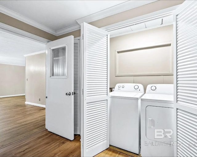 laundry room featuring washer and dryer, crown molding, and light hardwood / wood-style flooring