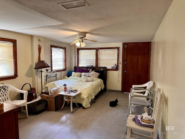 bedroom featuring a textured ceiling, ceiling fan, tile patterned flooring, and visible vents