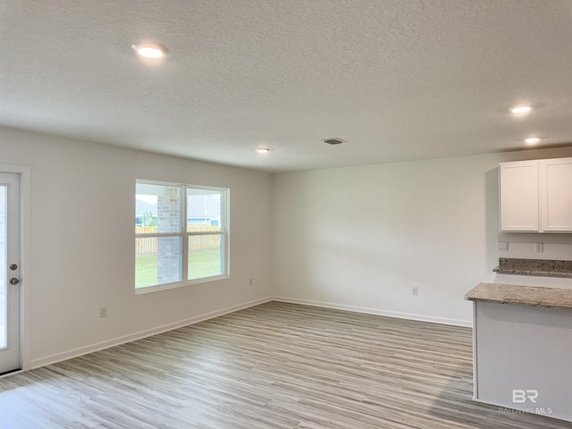 1036 Hayward Loop, Foley, AL 36535 - unfurnished living room with light wood-type flooring, a textured ceiling, recessed lighting, and baseboards