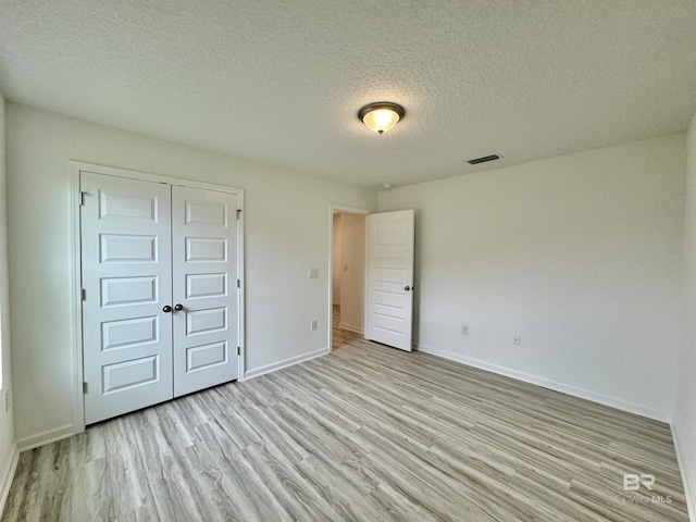 1036 Hayward Loop, Foley, AL 36535 - unfurnished bedroom with light wood-style flooring, baseboards, a textured ceiling, and a closet