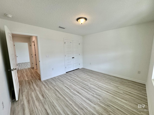 1036 Hayward Loop, Foley, AL 36535 - unfurnished bedroom with light wood finished floors, baseboards, a textured ceiling, and a closet