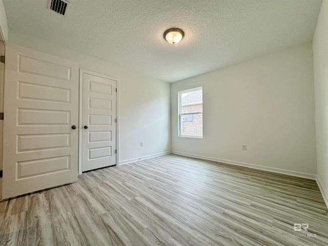 1036 Hayward Loop, Foley, AL 36535 - spare room featuring light wood-style flooring, a textured ceiling, and baseboards