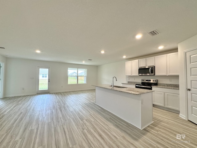 1036 Hayward Loop, Foley, AL 36535 - kitchen featuring appliances with stainless steel finishes, a sink, open floor plan, white cabinetry, and light wood-type flooring