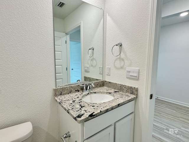 1036 Hayward Loop, Foley, AL 36535 - half bathroom with vanity, a textured wall, toilet, and wood finished floors