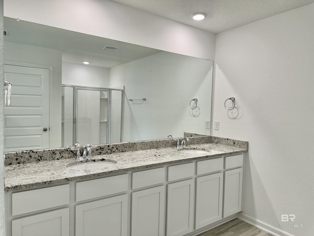 1036 Hayward Loop, Foley, AL 36535 - full bathroom with double vanity, a stall shower, wood finished floors, and baseboards