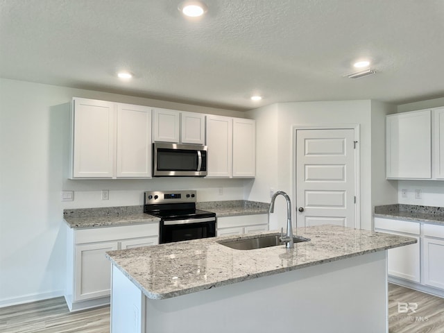1036 Hayward Loop, Foley, AL 36535 - kitchen with stainless steel appliances, a sink, light wood finished floors, white cabinetry, and a textured ceiling