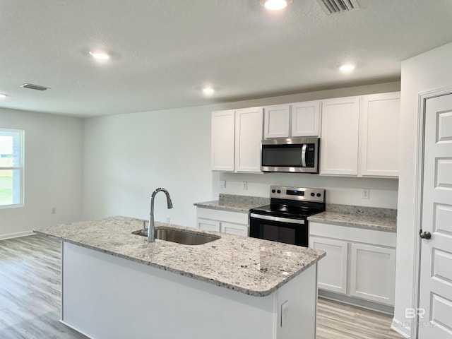 1036 Hayward Loop, Foley, AL 36535 - kitchen with stainless steel microwave, electric range oven, a sink, light wood-type flooring, and white cabinetry
