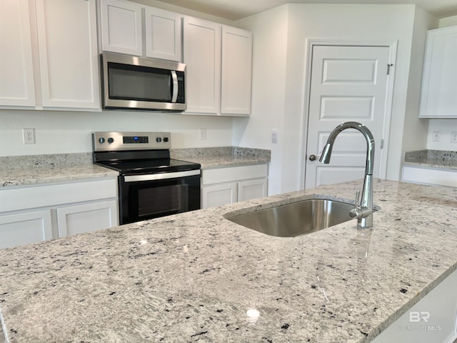 1036 Hayward Loop, Foley, AL 36535 - kitchen with appliances with stainless steel finishes, a sink, white cabinets, and light stone countertops