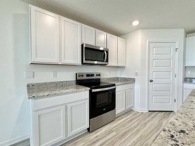 1036 Hayward Loop, Foley, AL 36535 - kitchen with appliances with stainless steel finishes, light wood finished floors, white cabinets, baseboards, and light stone counters