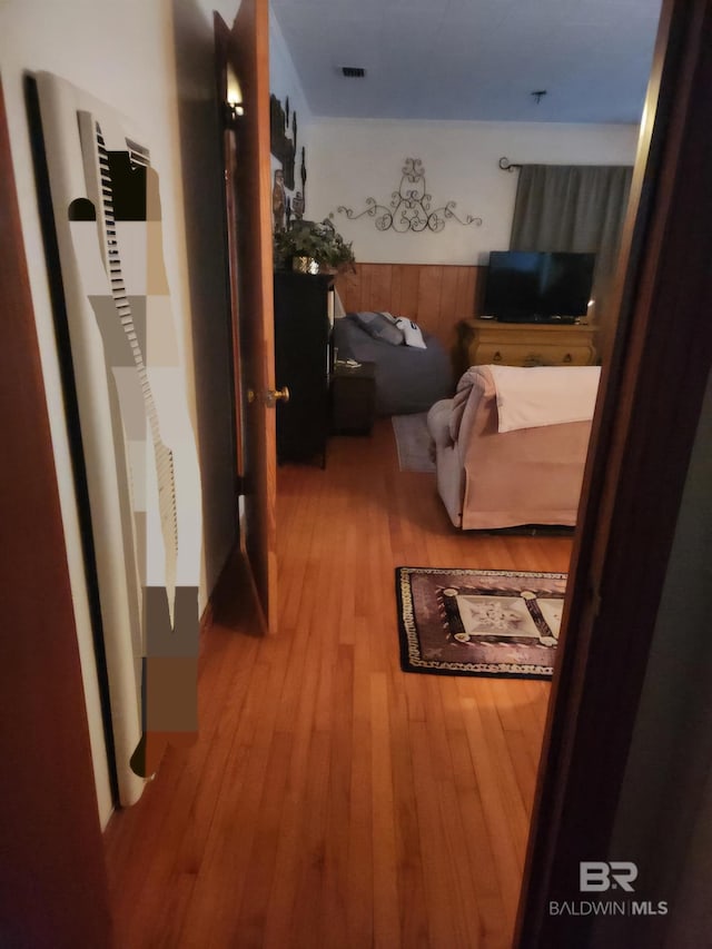 corridor with wood-type flooring, a heating unit, and visible vents
