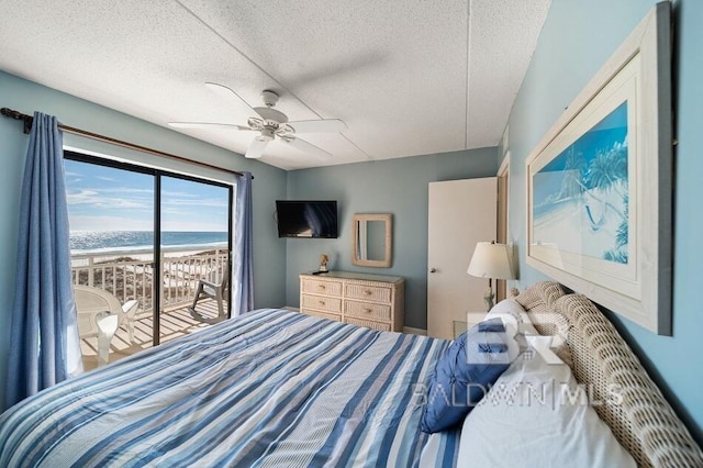 bedroom featuring access to exterior, a water view, a textured ceiling, and ceiling fan