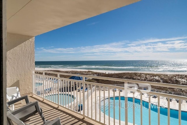 balcony with a water view, a community pool, and a view of the beach