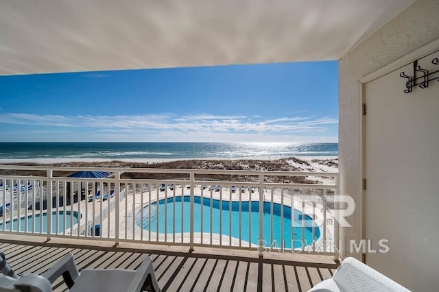 balcony with a water view and a view of the beach