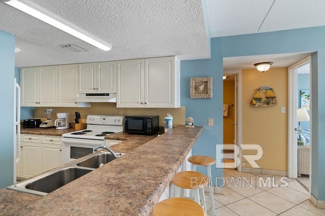 kitchen featuring white cabinetry, light tile patterned flooring, white range with electric cooktop, a breakfast bar area, and a textured ceiling