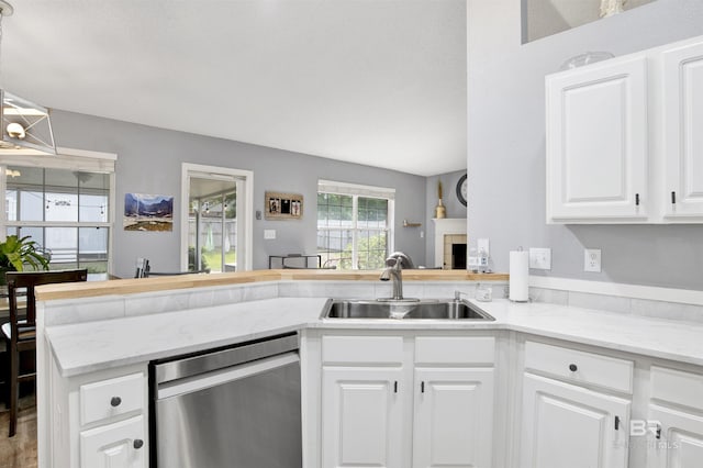 kitchen with dishwasher, a sink, white cabinets, a peninsula, and light stone countertops