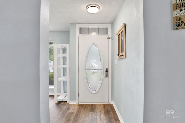 doorway to outside with wood finished floors, baseboards, and a textured ceiling