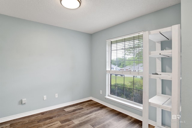unfurnished room with dark wood-style floors, baseboards, and a textured ceiling