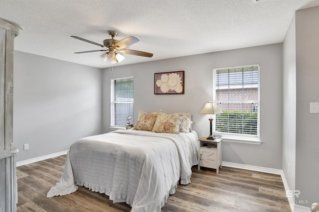bedroom with wood finished floors, baseboards, a textured ceiling, and a ceiling fan
