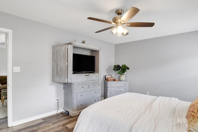 bedroom featuring wood finished floors, baseboards, and ceiling fan
