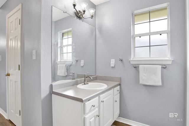 bathroom with a chandelier, baseboards, and vanity