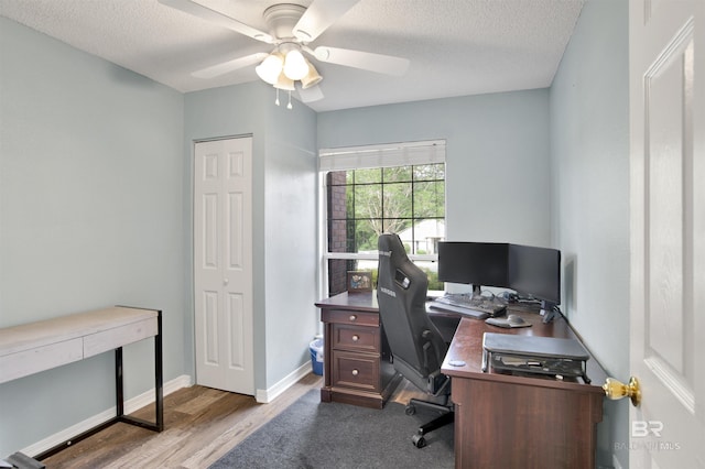 home office with a ceiling fan, a textured ceiling, wood finished floors, and baseboards