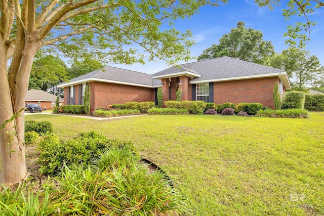ranch-style home with brick siding, a front lawn, and a shingled roof