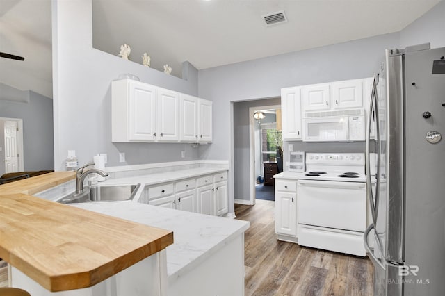 kitchen featuring white appliances, a sink, a peninsula, light wood-type flooring, and white cabinets
