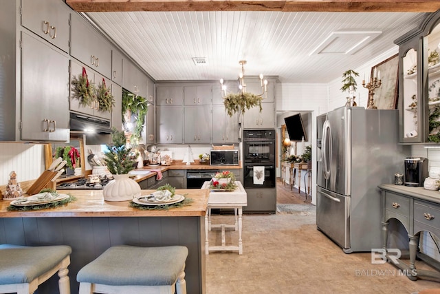 kitchen with black appliances, butcher block counters, gray cabinetry, a kitchen bar, and kitchen peninsula