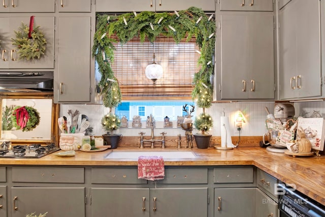 kitchen with sink, gray cabinets, range hood, wood counters, and stainless steel gas stovetop