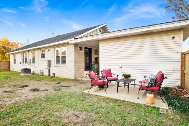 rear view of house with cooling unit, a patio, and a lawn