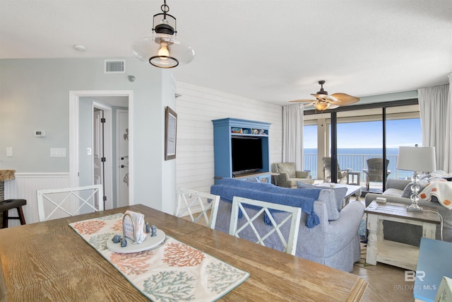 dining room featuring a wainscoted wall, tile patterned flooring, visible vents, and a ceiling fan