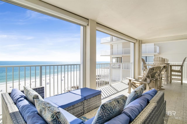 balcony with an outdoor hangout area, a water view, and a view of the beach