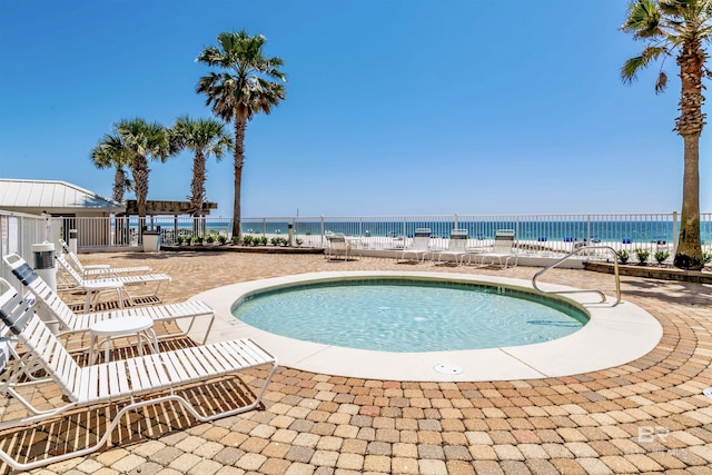 view of swimming pool featuring a patio, a water view, fence, and a hot tub