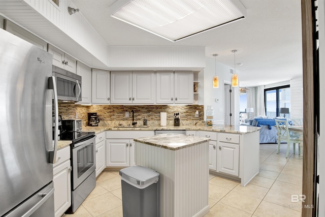 kitchen with light tile patterned floors, appliances with stainless steel finishes, a center island, a peninsula, and a sink