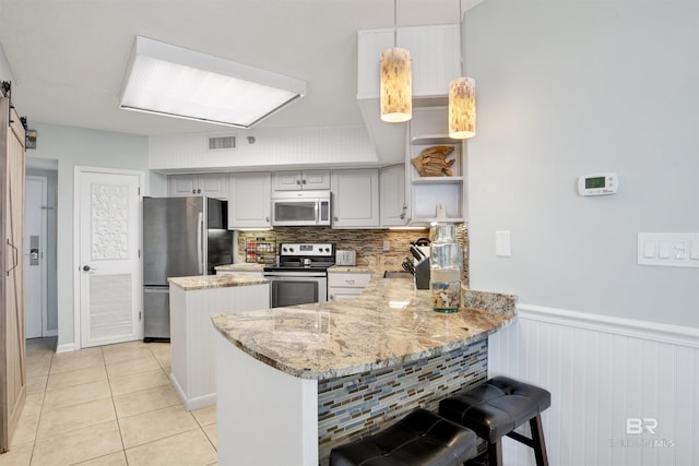 kitchen with light tile patterned floors, stainless steel appliances, open shelves, a barn door, and a peninsula