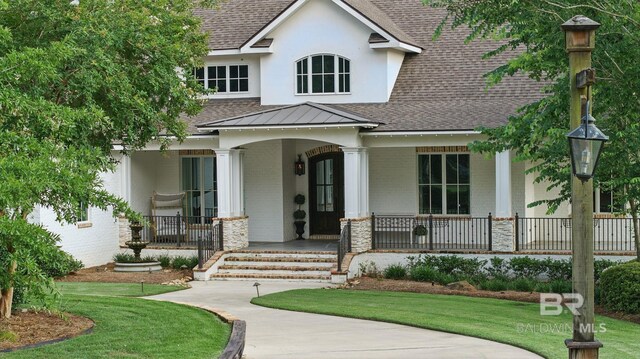 202 Paddle Creek Loop, Fairhope, AL 36532 - view of front of house with covered porch, a shingled roof, a front yard, a standing seam roof, and stone siding