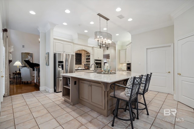 kitchen featuring hanging light fixtures, a kitchen island with sink, light tile patterned floors, stainless steel appliances, and crown molding