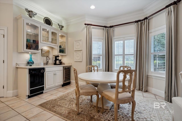 dining space with ornamental molding, light tile patterned floors, beverage cooler, and indoor wet bar