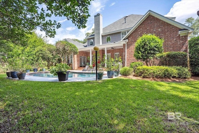 rear view of house with a lawn and ceiling fan